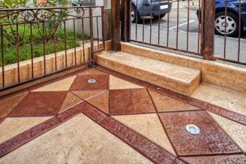 stamped patio with wrought iron fencing features embedded lighting at gate